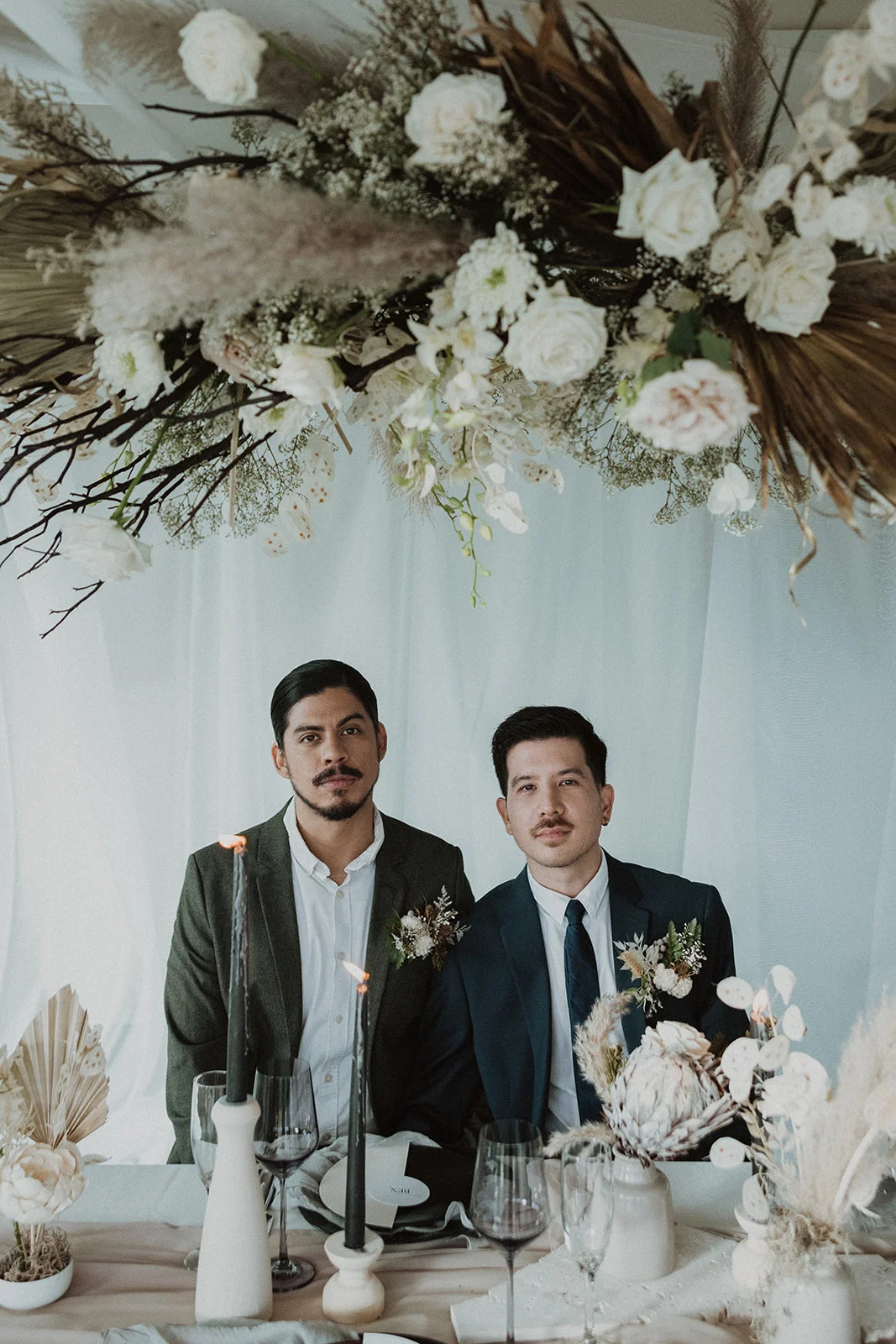 Elegant wedding table on Oʻahu with white roses, pampas grass, and dried palm leaves in a sophisticated floral arrangement.