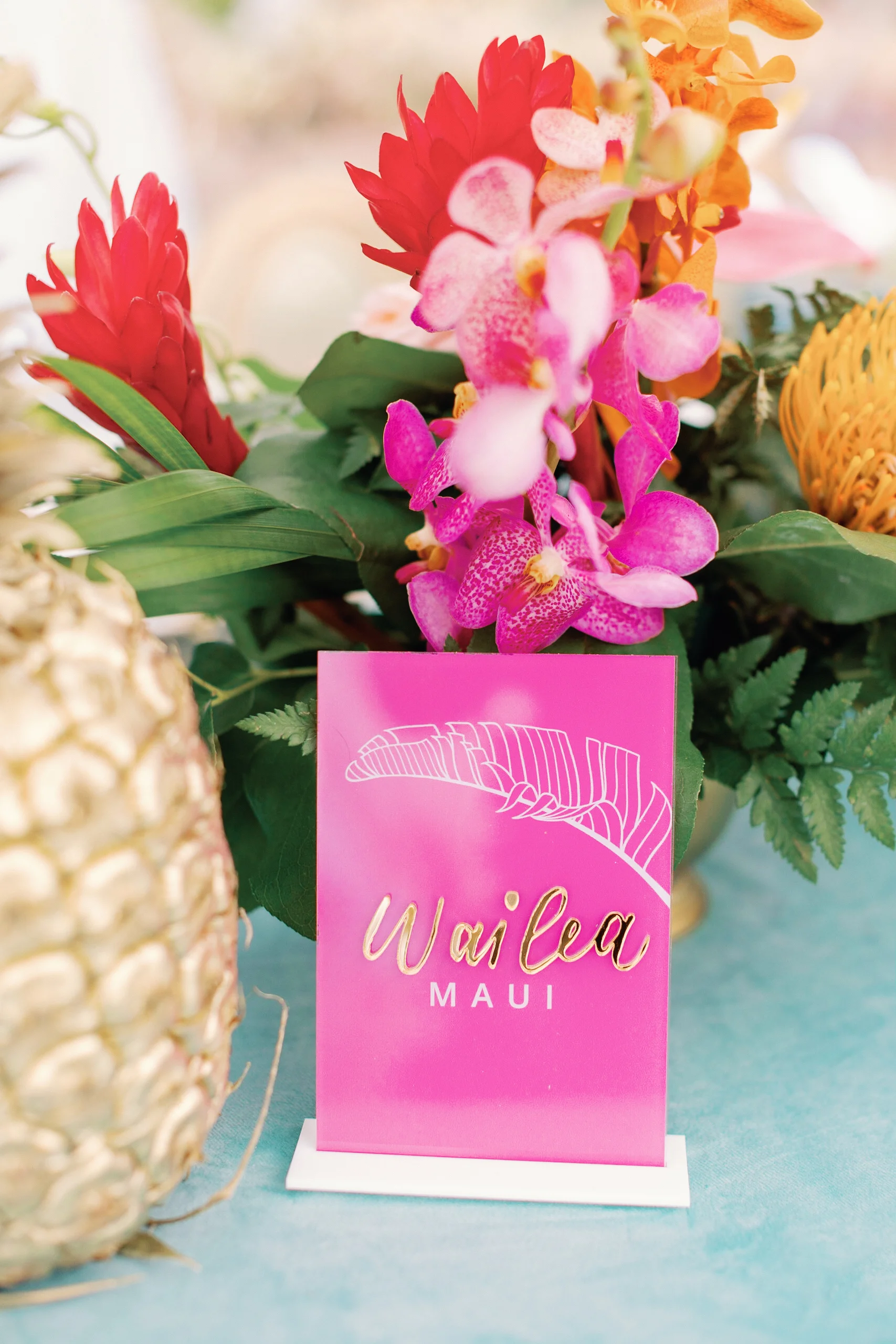 Tropical wedding floral arrangement at Loulu Palms with pink orchids, red ginger, and a pink Wailea Maui sign on a blue tablecloth. — Wedding Event Oahu Hawaii Florals Flowers Florist Creative Concepts by Jeff Alencastre