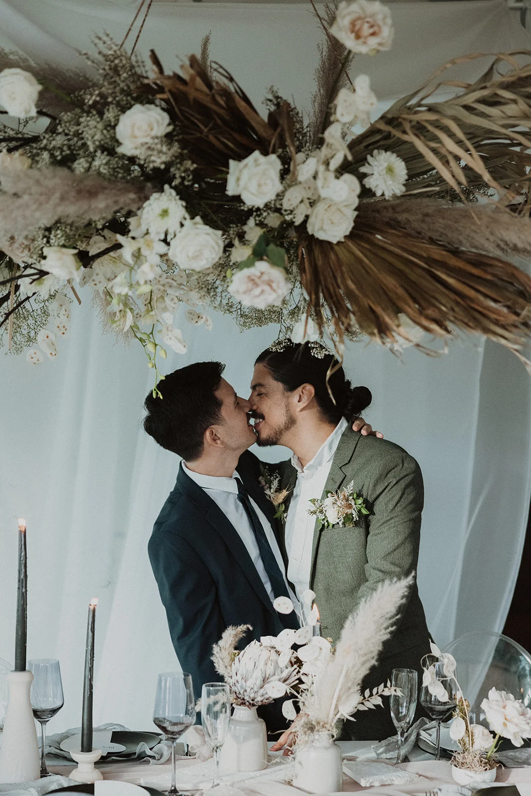 Romantic wedding scene on Oʻahu with pampas grass, white roses, and lush greenery over a table with elegant decor.