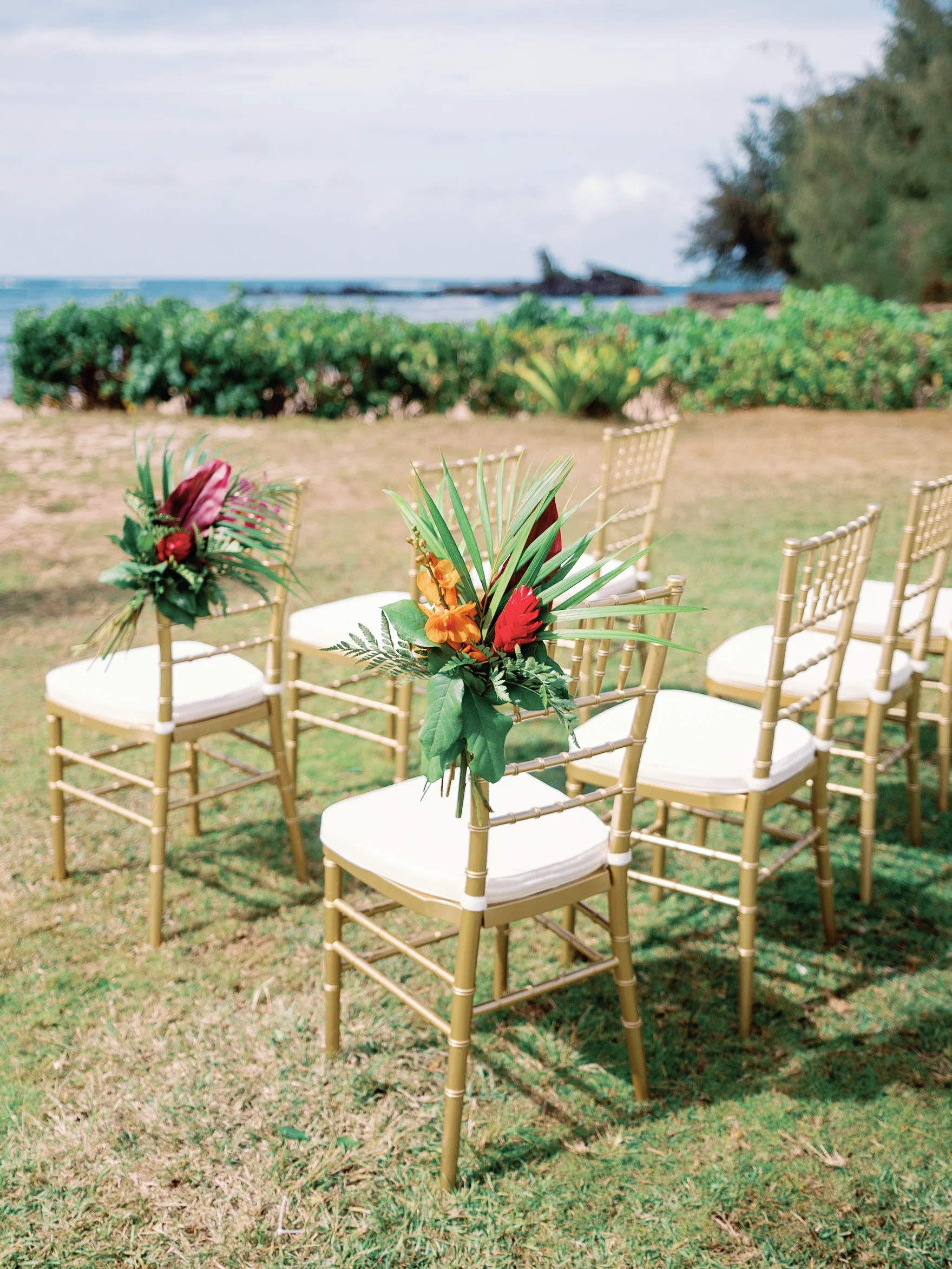 Beachfront wedding chairs at Loulu Palms, Oʻahu, adorned with tropical florals including red ginger and palm leaves. — Wedding Event Oahu Hawaii Florals Flowers Florist Creative Concepts by Jeff Alencastre