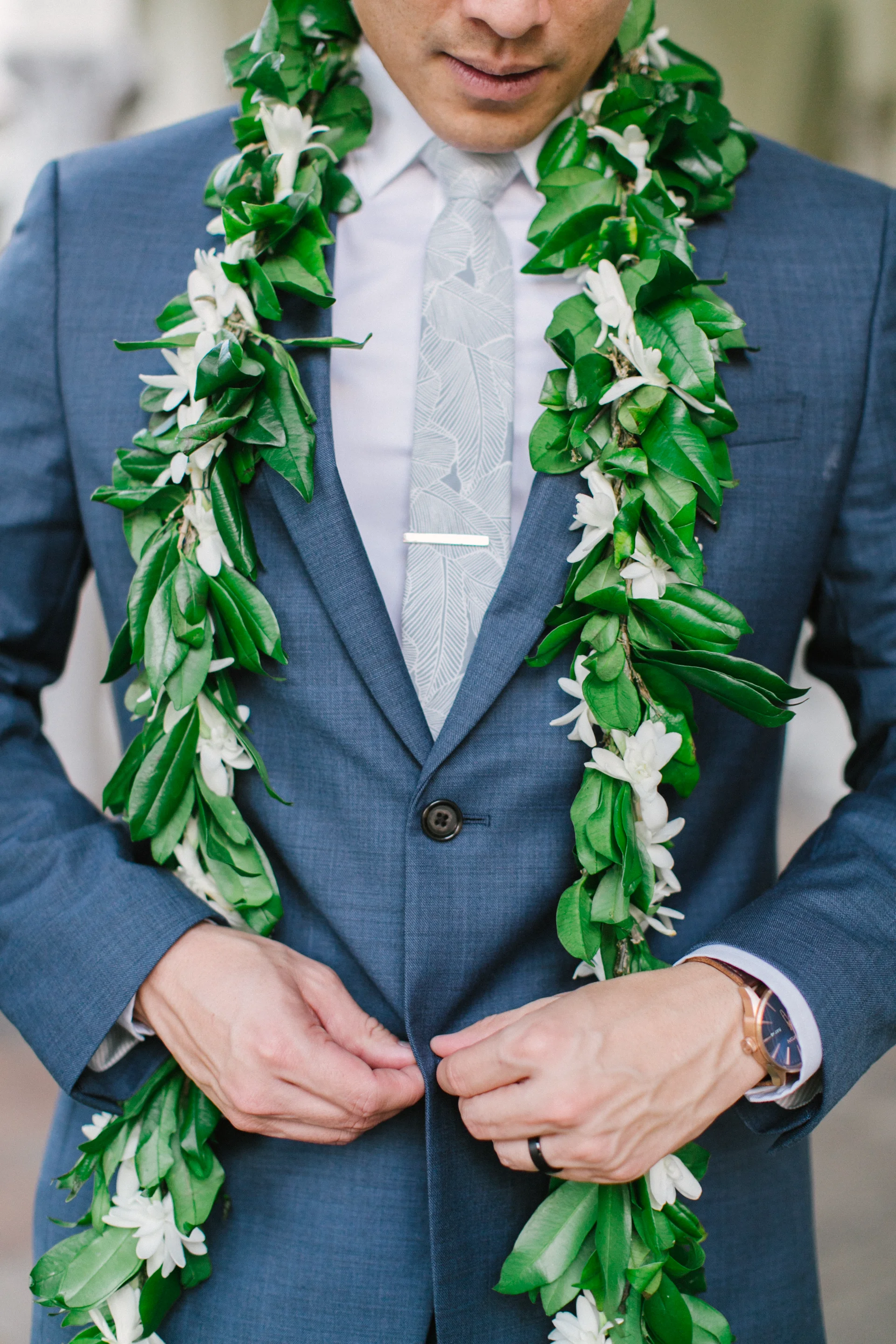 groom in blue suit with a white floral lei at Cafe Julia wedding on Oʻahu