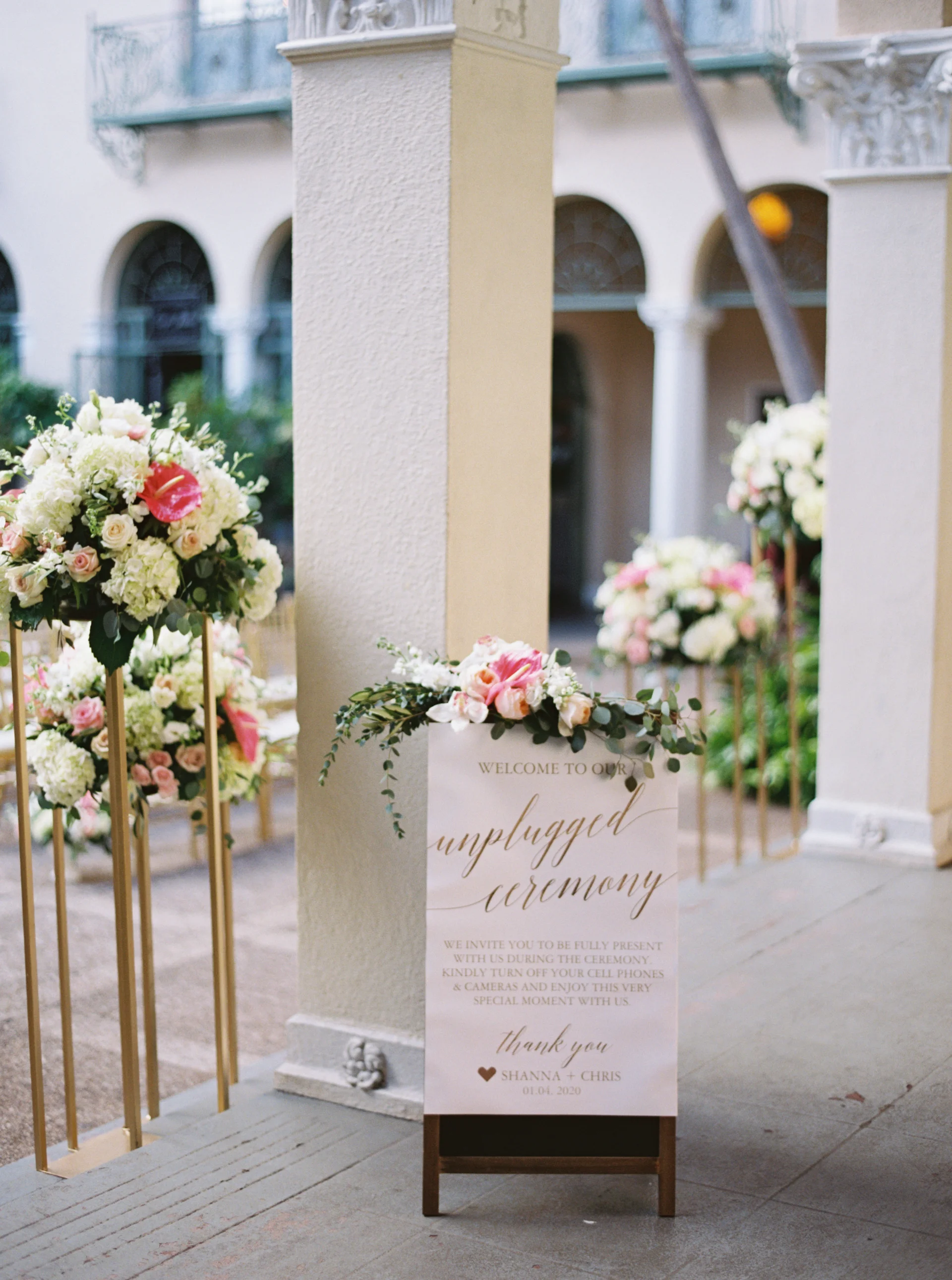 Elegant wedding floral arrangement with pink and white flowers on gold stands at Cafe Julia, Oʻahu wedding venue.