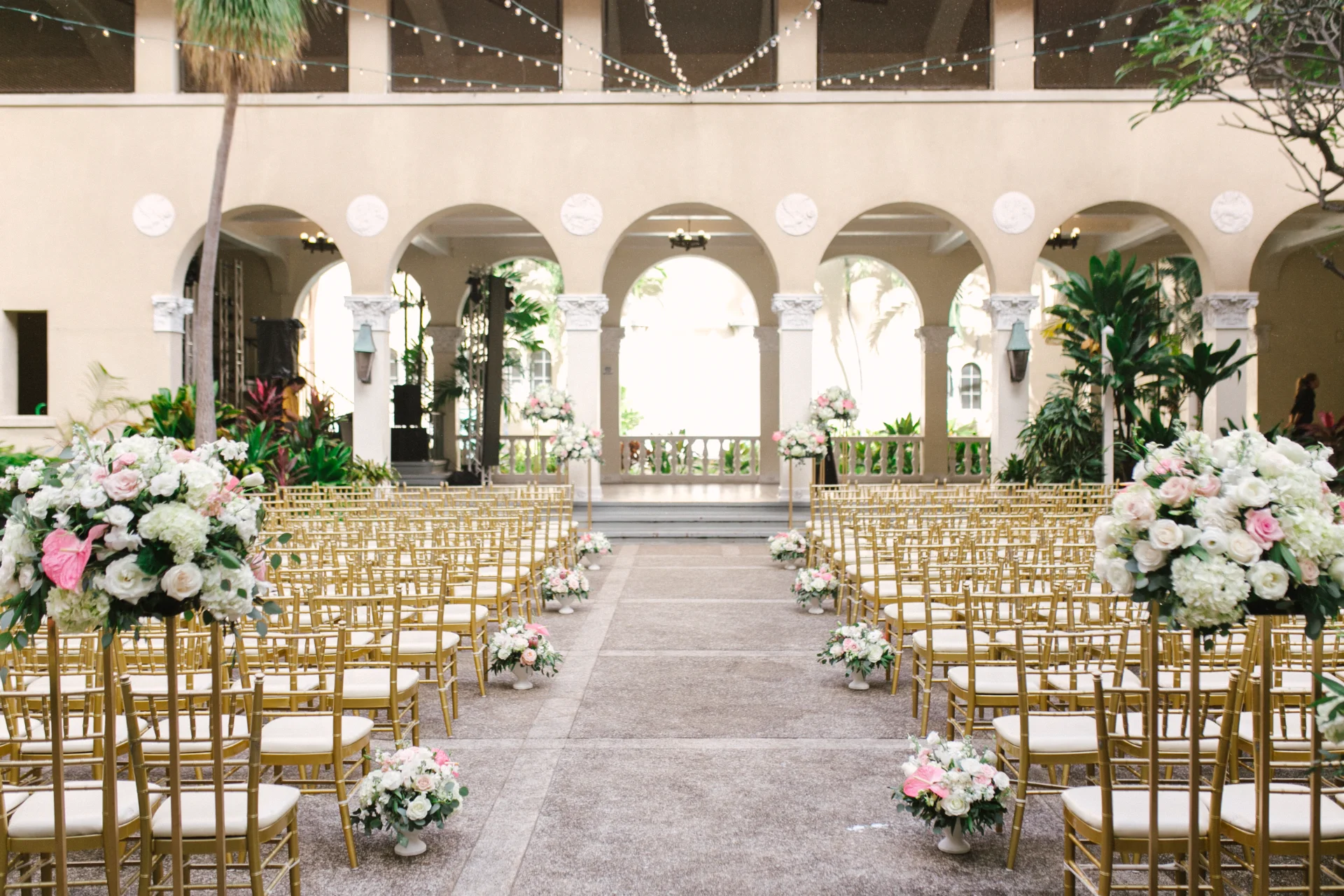 Elegant wedding setup at Cafe Julia, featuring gold chairs and lush floral arrangements with white and pink roses on Oʻahu, Hawaii.