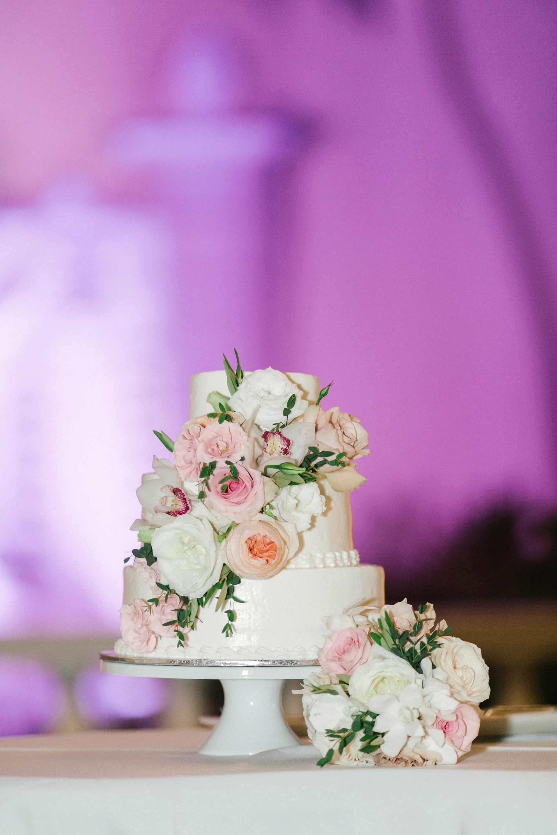 Elegant wedding cake with white and pink roses and greenery at Cafe Julia, Oʻahu, Hawaii.